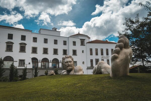 Dramatic sculpture and building facade at Ciudad Cayala amidst cloudy skies.