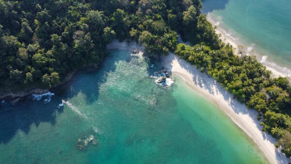 Stunning aerial shot of the lush coast and clear water at Manuel Antonio Beach in Costa Rica.